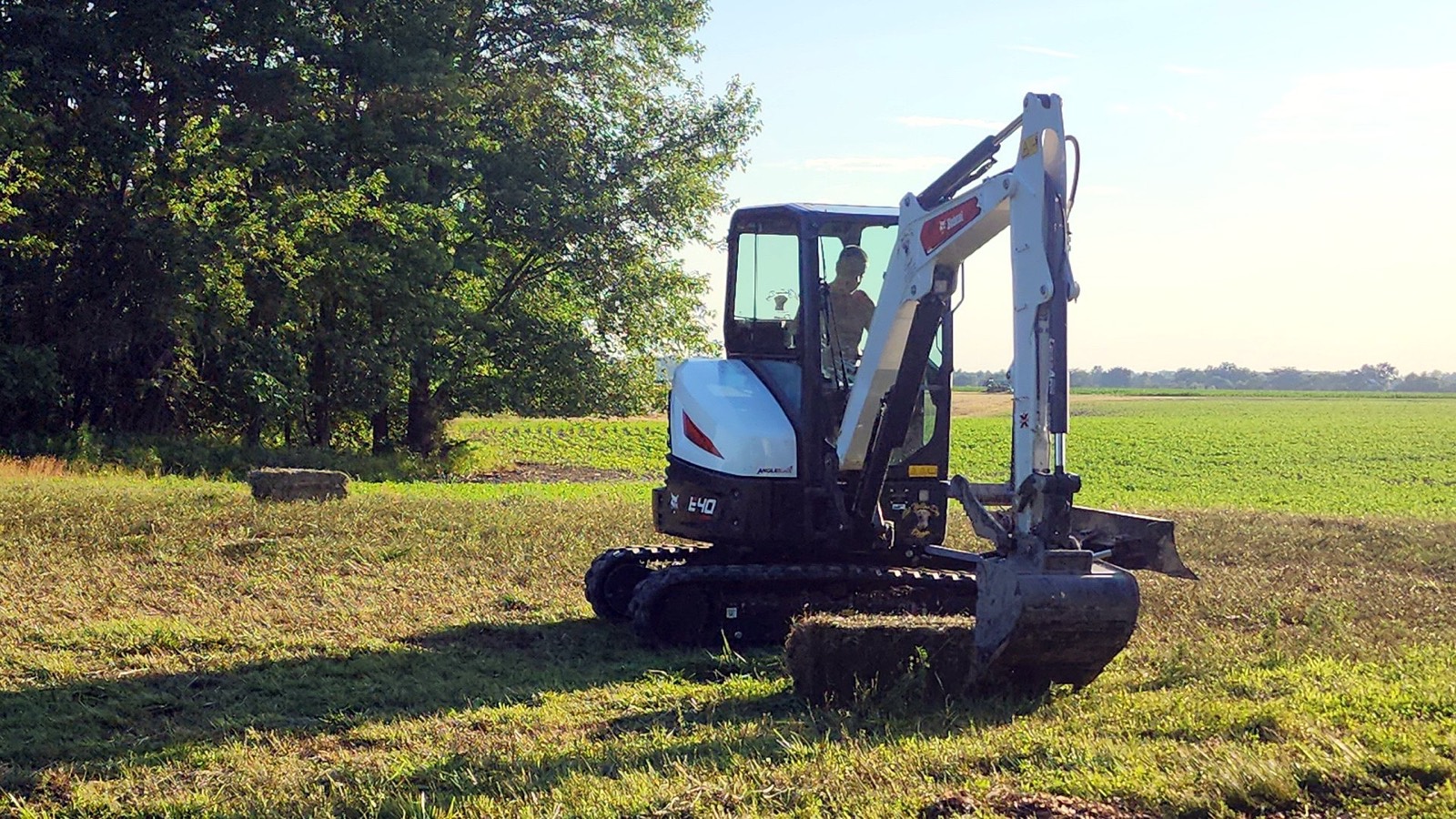 Mini excavator working along a rural field edge